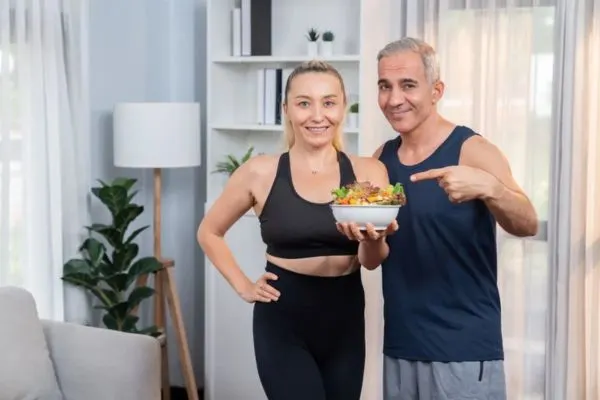 Couple actif tenant un bol de salade saine pour accompagner la perte de poids