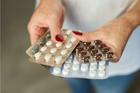 Plaquettes de comprimés dans les mains, illustrant les traitements et changements hormonaux