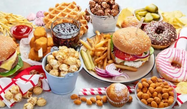 Assortiment de fast-food et produits ultra-transformés (burger, frites, donuts, soda), aliments à éviter pendant la ménopause