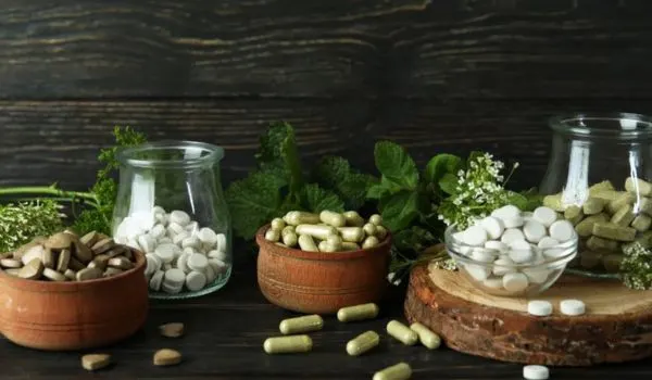 Pots et pilules de compléments alimentaires avec plantes, sur une table en bois