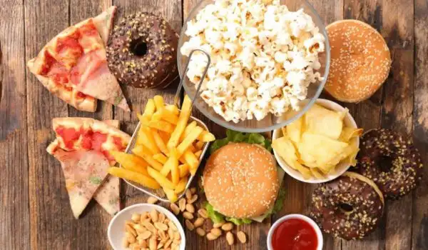 assortiment d’aliments ultra-transformés/fast-food (pizza, frites, burger, chips, donuts), illustrant les choix fréquents à limiter