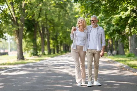 Couple senior marchant paisiblement en pleine nature, visiblement en bonne santé et souriant