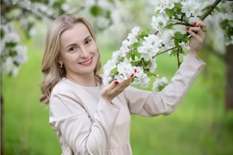 Femme souriante dans un jardin fleuri, symbolisant le bien-être retrouvé après traitement de la sécheresse vaginale