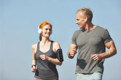 Homme et femme de plus de 50 ans en tenue de sport, pratiquant une activité physique en plein air.