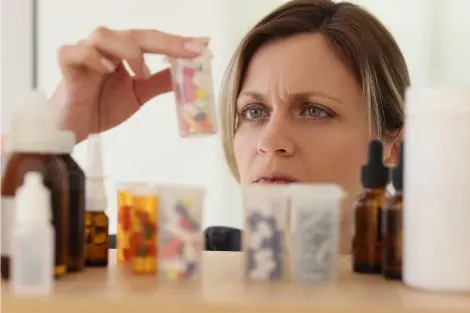 Une femme examine des médicaments et compléments avec inquiétude