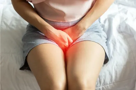 Femme souffrant d'irritation intime, mains posées sur le bas-ventre,
symptôme de sécheresse vaginale après 50 ans