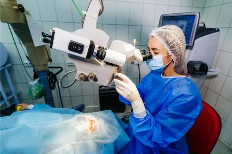 Personnel médical en tenue opératoire utilisant un microscope en salle de chirurgie