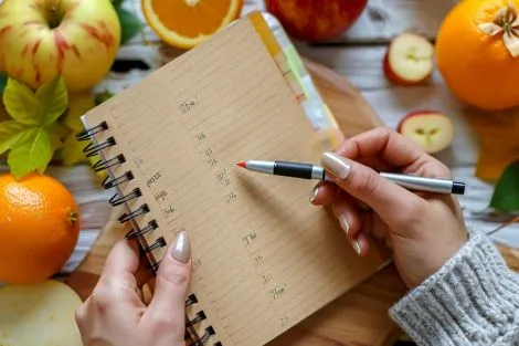 une femme ecrivant dans un cahier entouree de fruits frais dans un cadre
interieur confortable