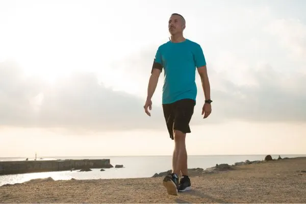 Personne de plus de 50 ans en marche tranquille sur une plage pour entretenir sa forme