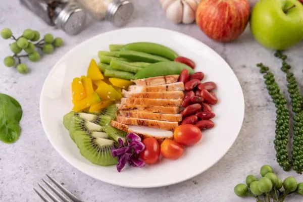 Assiette équilibrée avec protéines maigres, légumes verts, noix et fruits à faible index glycémique