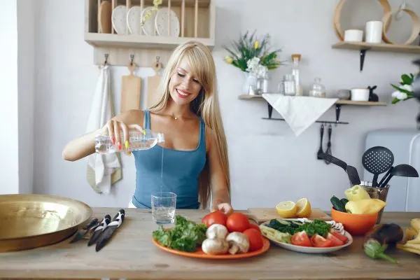 Femme de plus de 50 ans qui prépare des aliments simples et s’hydrate avant un jeûne hydrique