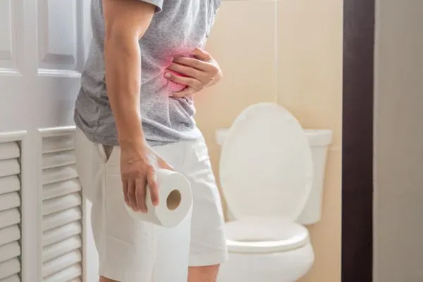 homme dans les toilettes sa main tient son ventre qui a mal a cause d'une forte constipation