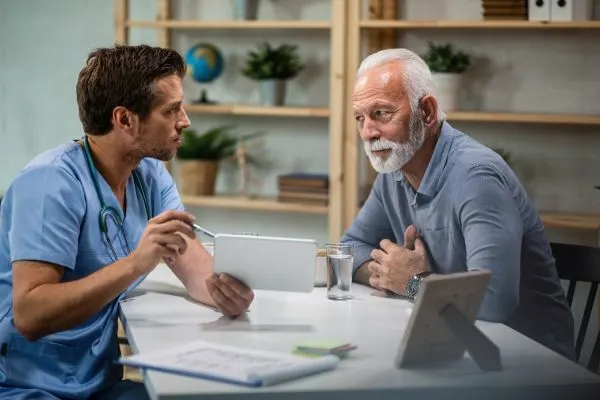 Médecin expliquant à un patient de plus de 50 ans les contre-indications du jeûne hydrique