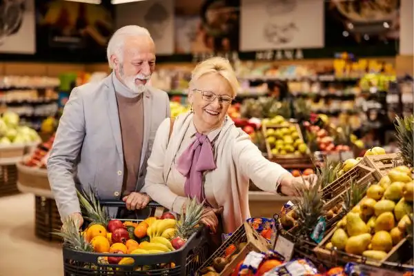 couple de personnes âgées souriant font leur courses au supermarché illustrant les moyens naturels de soutenir la serotonine