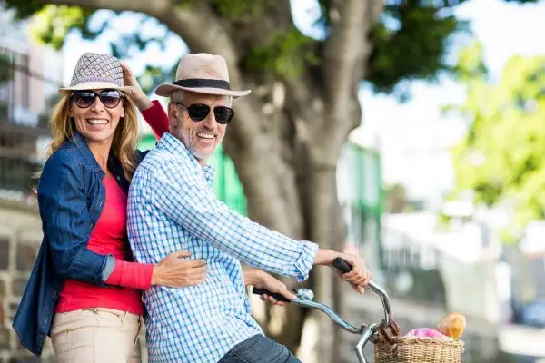 Couple de seniors en velo dehors au soleil avec lunettes de soleil, symbolisant une vision préservée après un zona ophtalmique