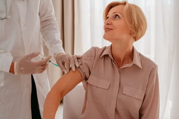 Infirmièr présentant une seringue de vaccin à un adulte de plus de 50 ans pour la prévention du zona