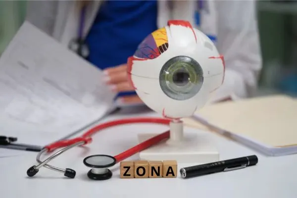 un oeil de manequin posé sur un bureau d'ophtalmologiste et qui est ecrit zona