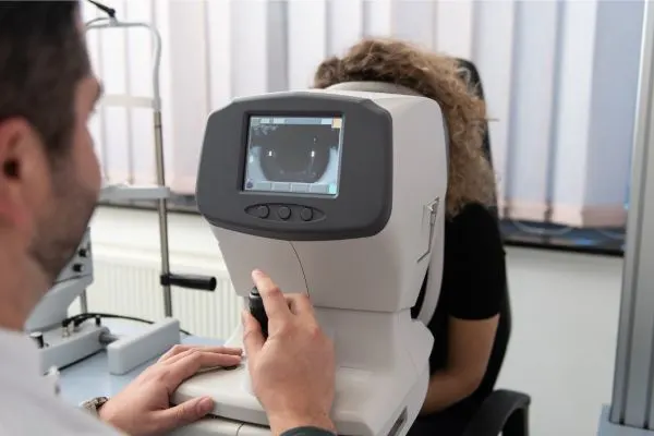 Examen de la vue par tonométrie à air pulsé : gros plan sur l'œil d'un patient et l'appareil projetant un jet d'air invisible, réaction réflexe légère de l'œil.