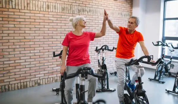 Seniors célébrant la fin d'une séance de sport en salle par un "high five", signe de réussite et convivialité