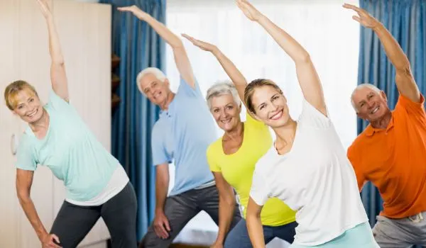 Groupe de seniors suivant un cours de gym douce avec des mouvements d'étirement latéral