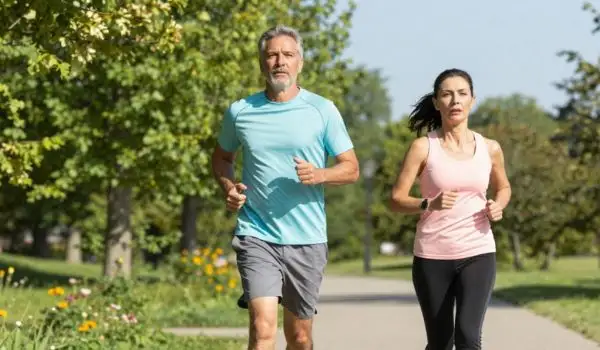 Couple qui court à rythme facile sur un chemin, pour perdre du poids après 50 ans.